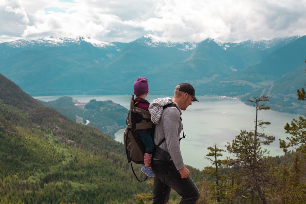 Baby Mountain A baby on it's dad back overlooking a lake and mountains.
